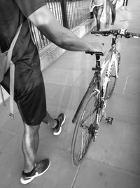 Low section of young man with bicycle walking on street