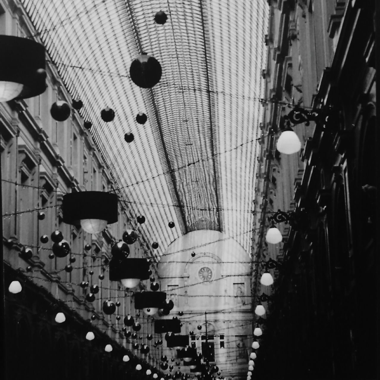 indoors, ceiling, in a row, illuminated, lighting equipment, architecture, hanging, built structure, low angle view, repetition, large group of objects, abundance, incidental people, no people, order, interior, decoration, diminishing perspective, metal, arrangement