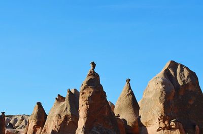 Low angle view of rocks against clear blue sky