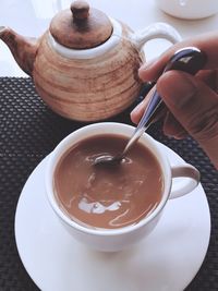 Cropped hand of man stirring tea in cup