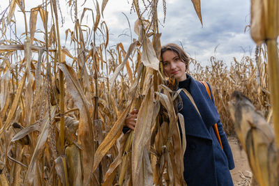 Woman standing in autumn in cornfield and looking at camera