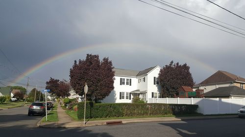 Rainbow over road in city against sky