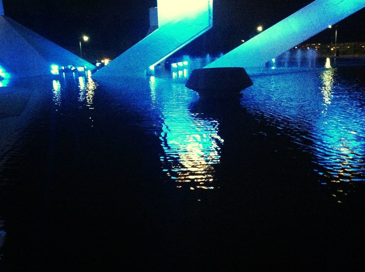 water, illuminated, night, built structure, reflection, architecture, blue, waterfront, silhouette, building exterior, lighting equipment, river, rippled, street light, sea, dusk, outdoors, railing, dark, light - natural phenomenon