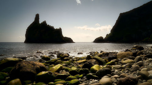 Panoramic view of rocks on beach against sky