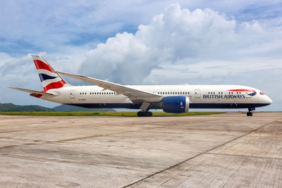 Airplane on airport runway against sky