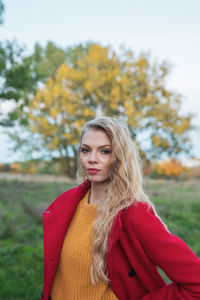 Portrait of beautiful young woman standing against tree