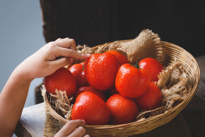 Cropped hand touching tomato in basket