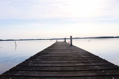 Wooden pier over lake against sky