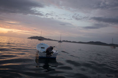 Boats in sea at sunset