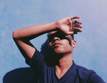 Portrait of young man looking away while standing against wall