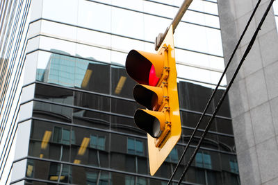 Low angle view of stoplight against modern building in city