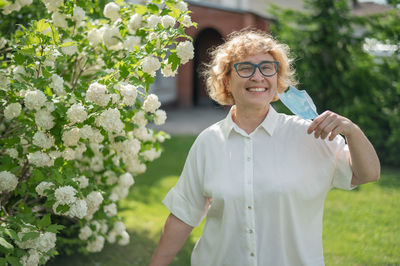 Portrait of smiling young woman standing by plants