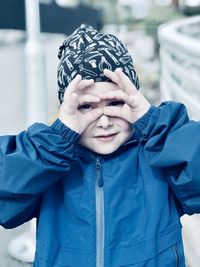 Portrait of boy looking through hands mask