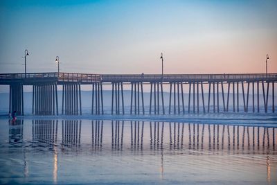 Pier on sea against clear sky at sunset