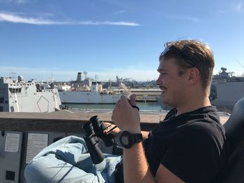 Close-up of man using smart phone against sky