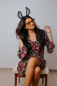 Beautiful young woman sitting against wall