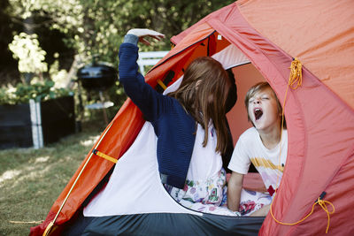 Brother and sister in tent in backyard