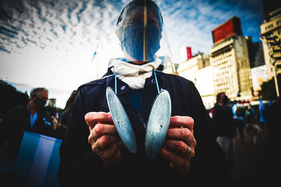People holding umbrella in city against sky