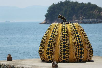 Close-up of yellow umbrella by sea against sky