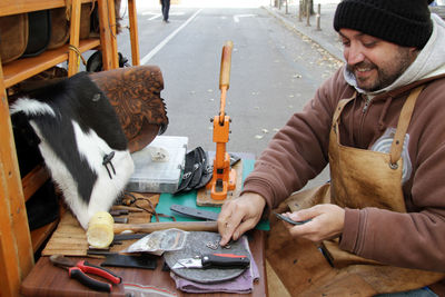 Man working on leather while sitting at table on road