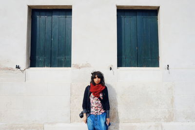 Young woman standing against wall