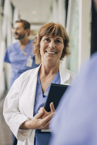 Female mature physician looking away while standing in hospital