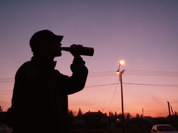 Silhouette of woman standing against sky at sunset