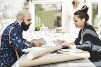 Side view of male and female architects working at yard