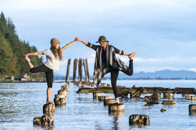 Two women do yoga on the remains of an old pier in bellingham, wa