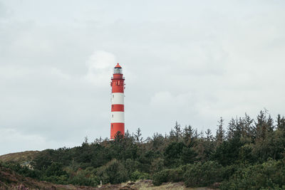 Lighthouse by sea against sky