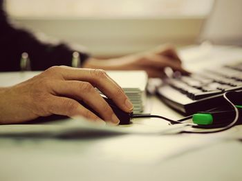 Cropped hand of woman working on computer at desk