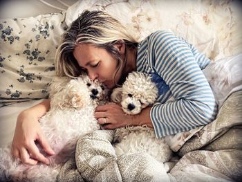 High angle view of woman kissing dog on bed