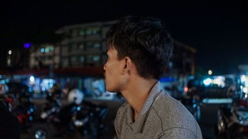 Portrait of young man looking at city street at night