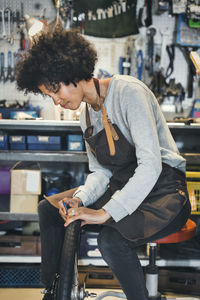 Mid adult female mechanic repairing bicycle tire in workshop