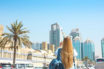 Rear view of woman by buildings against sky