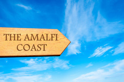 Low angle view of road sign against blue sky