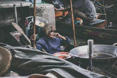 Senior woman sitting on floating market at river