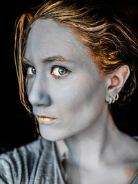 Close-up portrait of a young woman over black background