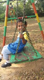 Boy sitting on swing at playground