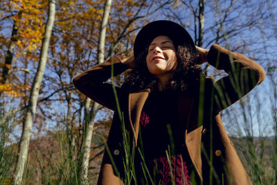 Portrait of smiling young woman standing against plants