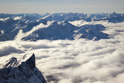 Dramatic panorama of snow capped mountains breaking through sea of clouds.