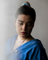 Close-up of young woman standing against wall