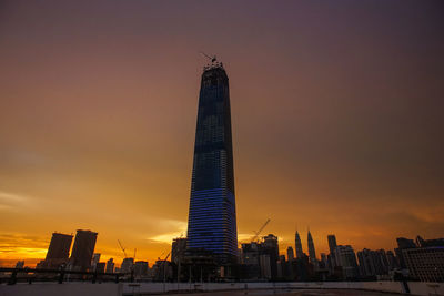 Modern buildings in city against sky during sunset