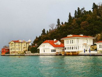 Houses by sea against sky in city