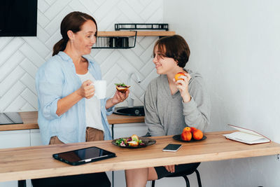 Mother and daughter eating food in kitchen