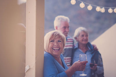 Happy friends with wineglasses standing at balcony