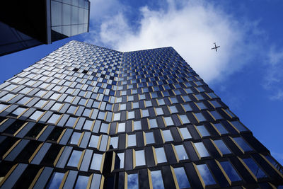 A tall skyscraper from the front with airplanes flying close by