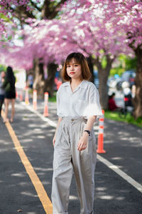 Portrait of smiling young woman standing on road in city