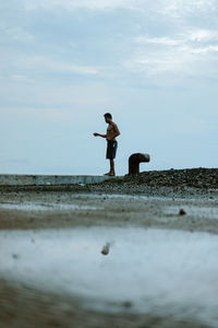 Rear view of woman standing on beach against sky