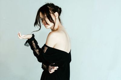 Portrait of young woman standing against white background